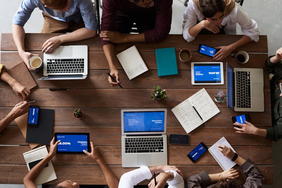 Overhead view of a diverse team in a business meeting using laptops and tablets
